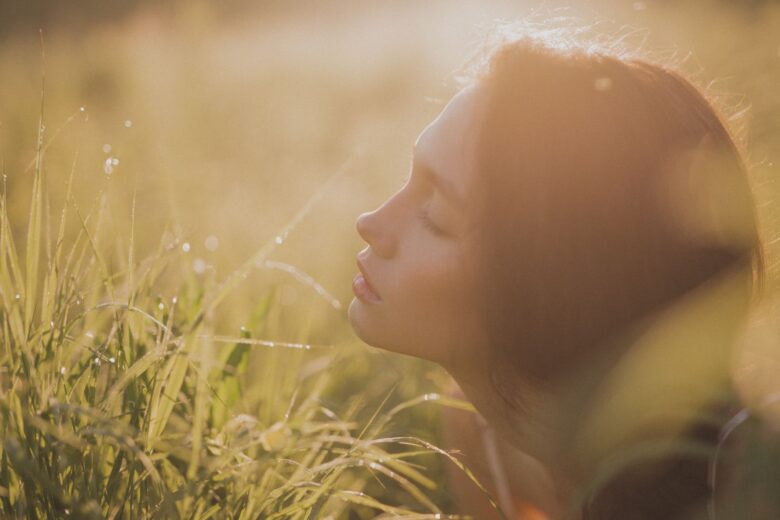 Mujer con los ojos cerrados en la naturaleza, en calma y presente, terapia Gestalt