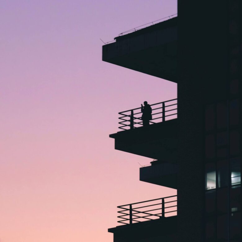 Silhouette of a person on a balcony at twilight, homesickness and identity